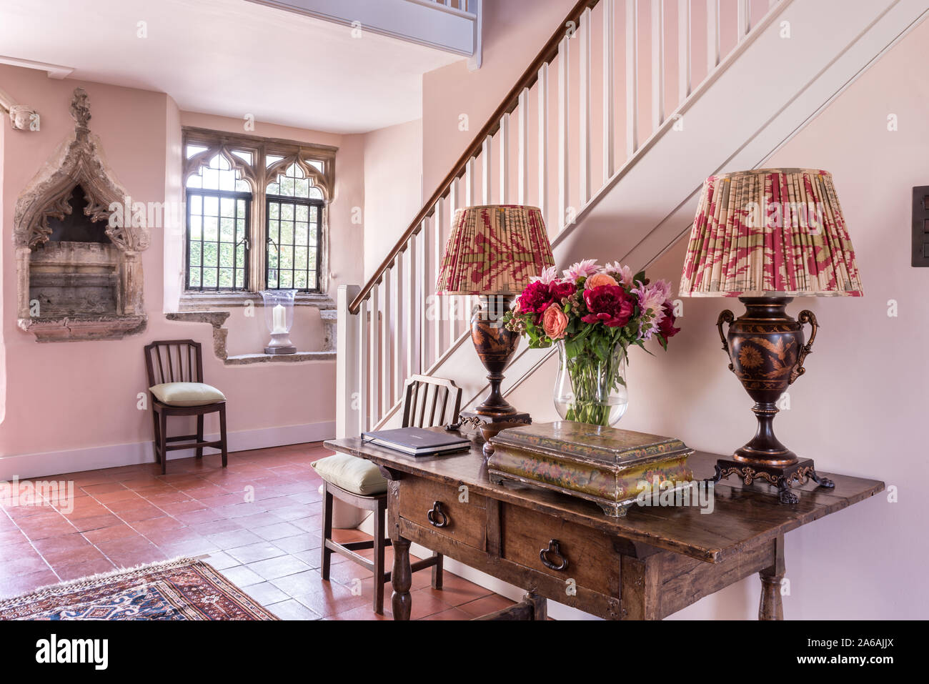 Il XIV secolo pietra intagliata nicchia. Conosciuta come una piscina o laver con lampade di antiquariato sul tavolo nella sala d'ingresso. Foto Stock