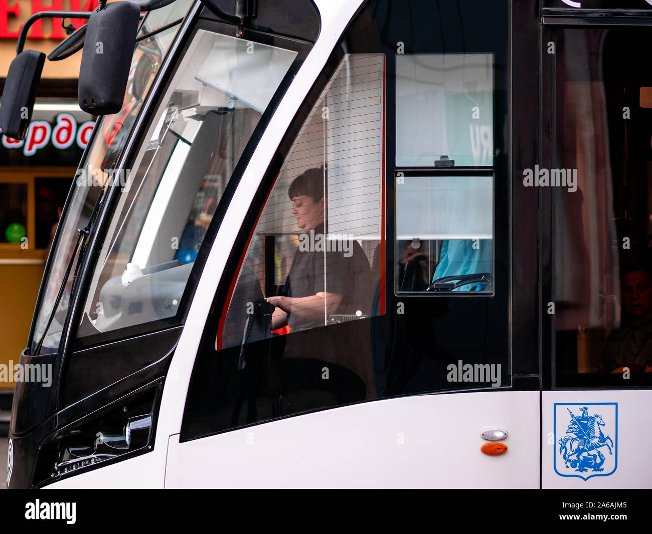 Mosca, Russia - 19 Ottobre 2019: moderno e basso piano tram "Vityaz-M' presso la fermata del bus. Lo stemma di Mosca è blu. Donna auto conducente in cabina Foto Stock
