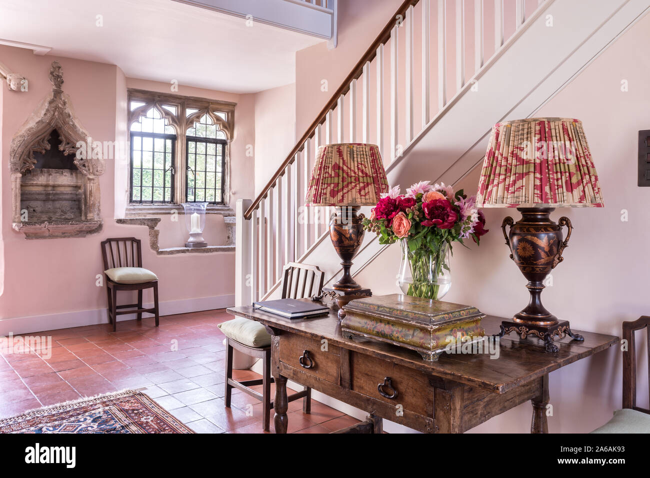 Il XIV secolo pietra intagliata nicchia. Conosciuta come una piscina o laver con lampade di antiquariato sulla tavola in entrnace hall. Foto Stock