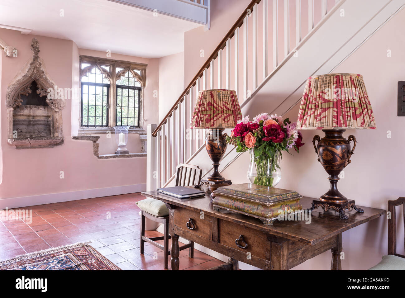 Il XIV secolo pietra intagliata nicchia. Conosciuta come una piscina o laver con lampade di antiquariato sul tavolo nella sala d'ingresso. Foto Stock