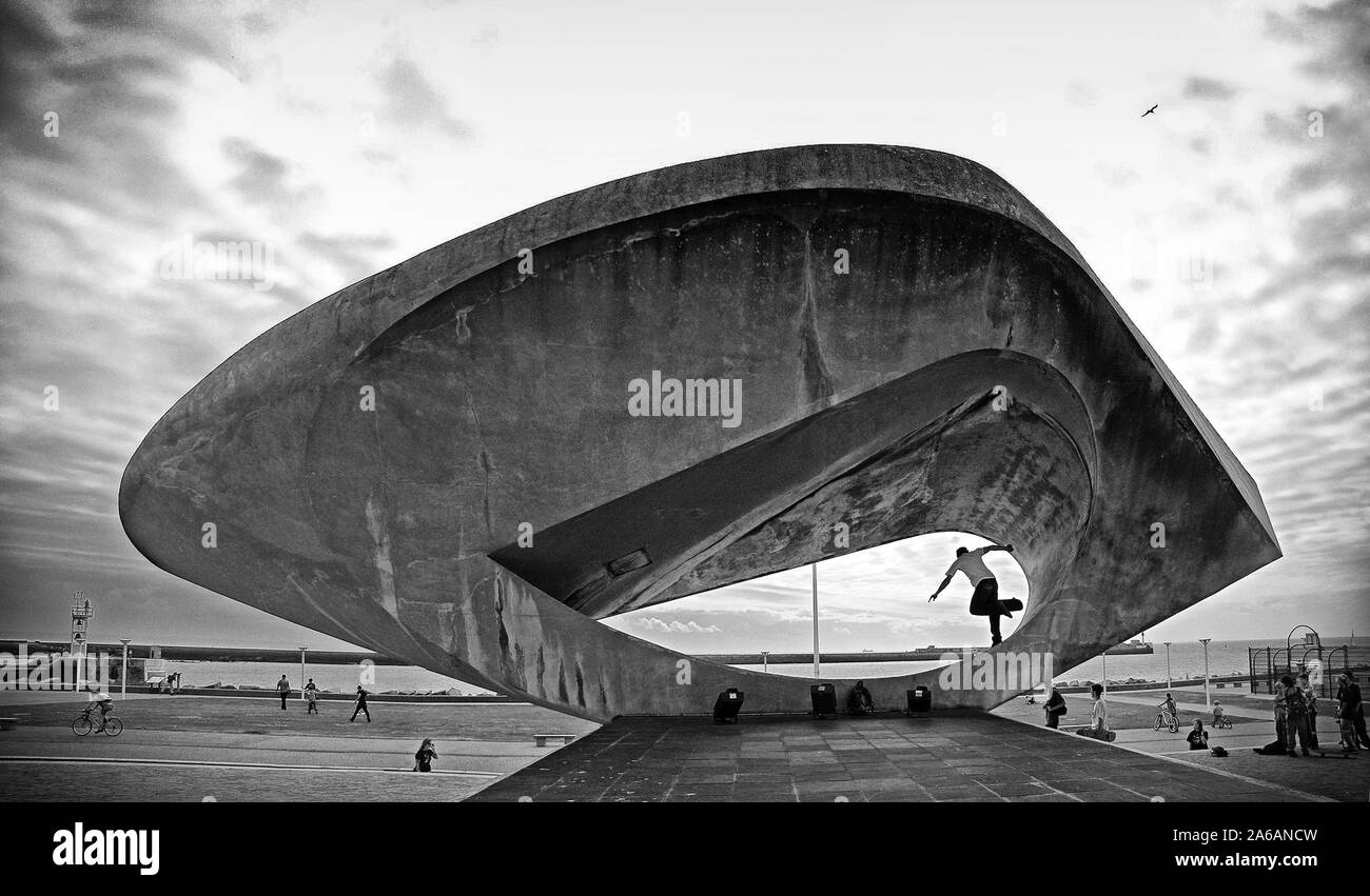 Guidatore di skateboard di eseguire un trick nel mezzo di 'il' segnale di scultura di Henri Georges ADAM (1904-1967) nella parte anteriore del Musée-maison de la culture nella città francese di Le Havre durante l'estate del 2005. Foto Stock