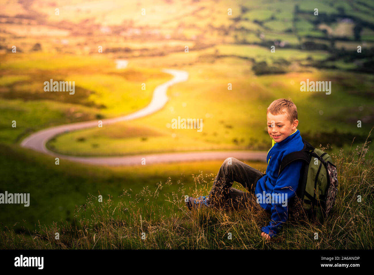 Un ragazzino con ADHD, autismo, sindrome di Aspergers seduto a ridere, felice mentre fuori trekking e alpinismo,il Grande Ridge, malattia mentale Foto Stock