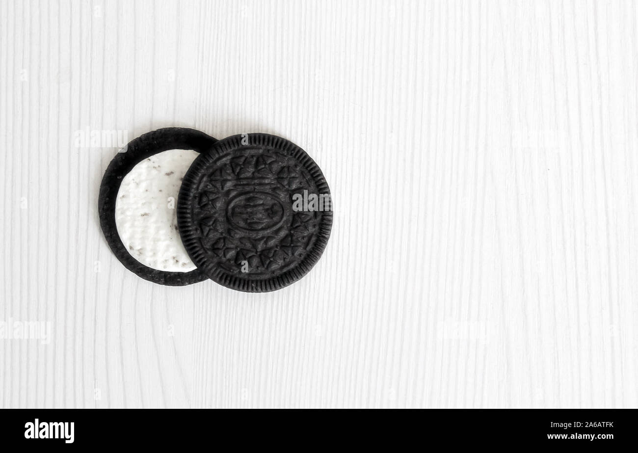 Due i cookie di nero disposti in due file con una crema bianca centro su un bianco sullo sfondo di legno. isolare lo sfondo. Foto Stock