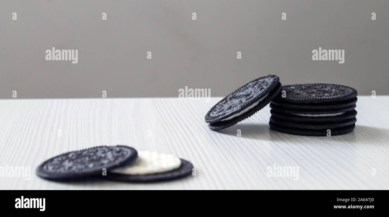 I cookie di nero pinnacle permanente con crema bianca centro su un bianco sullo sfondo di legno. Foto Stock