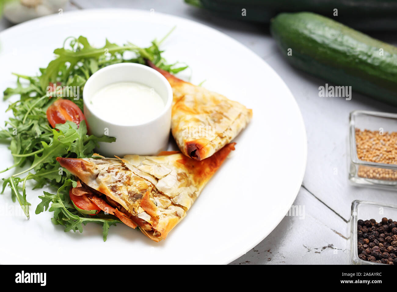 Frittelle fatte di filo impasto ripieno di verdure e funghi, serviti con salsa di aglio e insalata verde Foto Stock