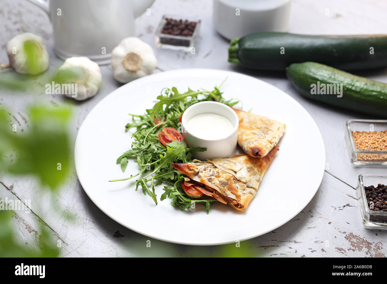 Frittelle fatte di filo impasto ripieno di verdure e funghi, serviti con salsa di aglio e insalata verde Foto Stock