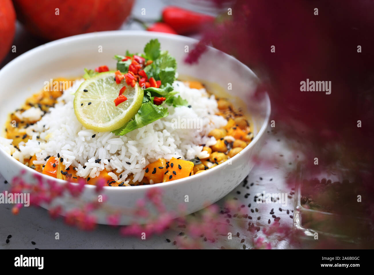 Arancione curry vegetariano con ceci, zucca, spinaci, coriandolo servito con riso basmatti. Composizione di autunno Foto Stock