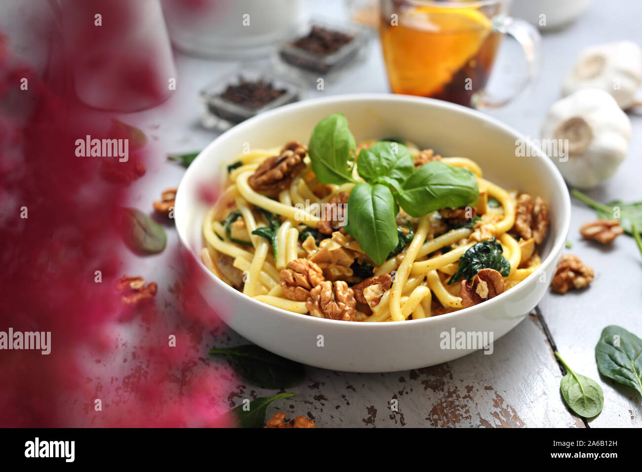 In autunno gli spaghetti al dente in una salsa alla panna con spinaci freschi, aglio, pollo e noci Foto Stock