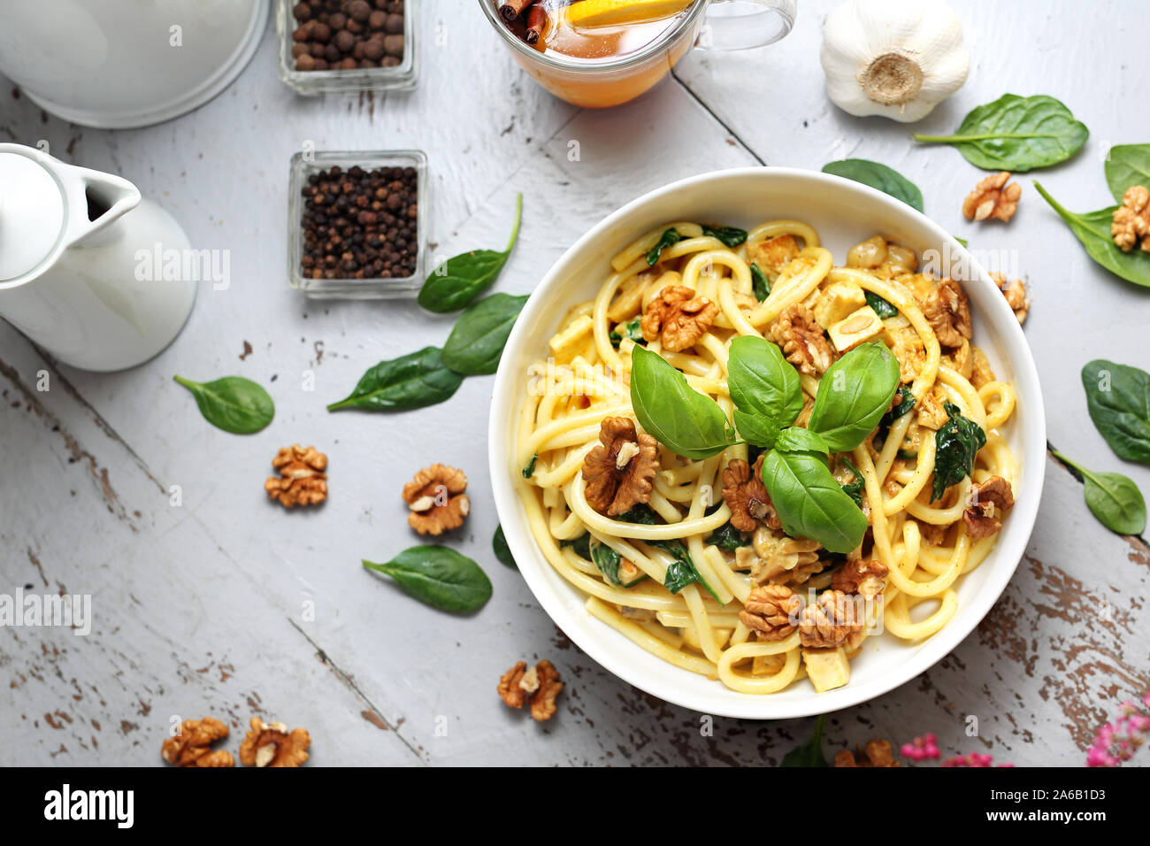 Pasta bucatini in una salsa alla panna con spinaci freschi, aglio, noci Foto Stock