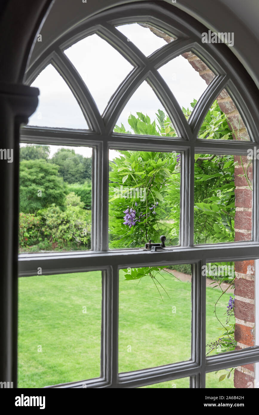 Vista attraverso la finestra a ghigliottina al giardino del XIV secolo English hall Foto Stock