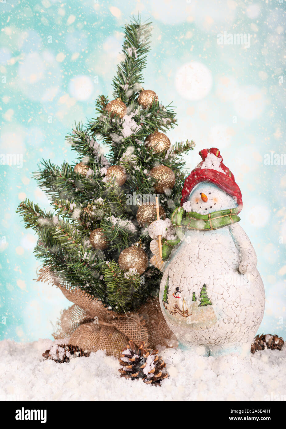 Pupazzo di neve e figurine di albero di Natale decorato con caduta di neve su un luminoso colorato Foto Stock