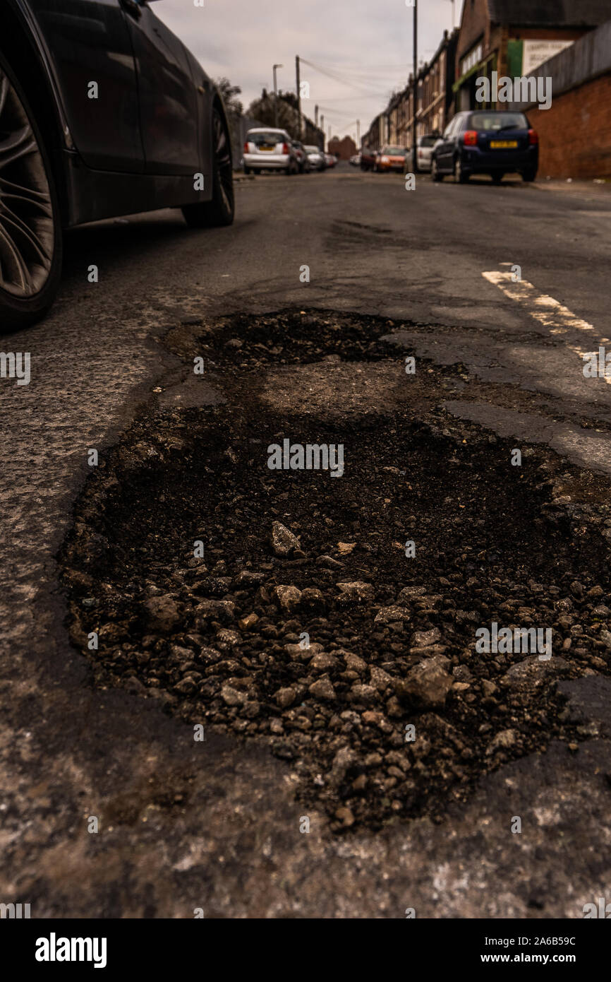 Danneggiato le superfici stradali, cavalcato con profonde buche che causano danni alle auto, biciclette e camion sulle strade e anche gli incidenti, Foto Stock