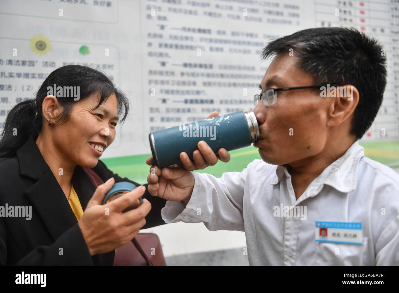 (191025) -- NANCHANG, 25 ottobre 2019 (Xinhua) -- Xiao Jiulin bevande acqua dalla sua moglie Huang Shuzhen dopo aver visto un paziente in una clinica presso Il Yangang villaggio in Duanwu township di Yudu County, Cina orientale della provincia di Jiangxi, 24 ottobre, 2019. Il 55-anno-vecchio Xiao Jiulin è un medico rurale all'orientale villaggio cinese. Quando aveva tre anni, Xiao fisicamente è stata disattivata a causa di una malattia che ha poi portato alla sua altezza solo mantenendo in 90 cm. La bassa statura provoca disturbi in tutti Xiao la vita, ma anche lo sospinse ad aspirare a essere un dottore che può aiutare i pazienti esenti da malattie. Nel 1989 W Foto Stock