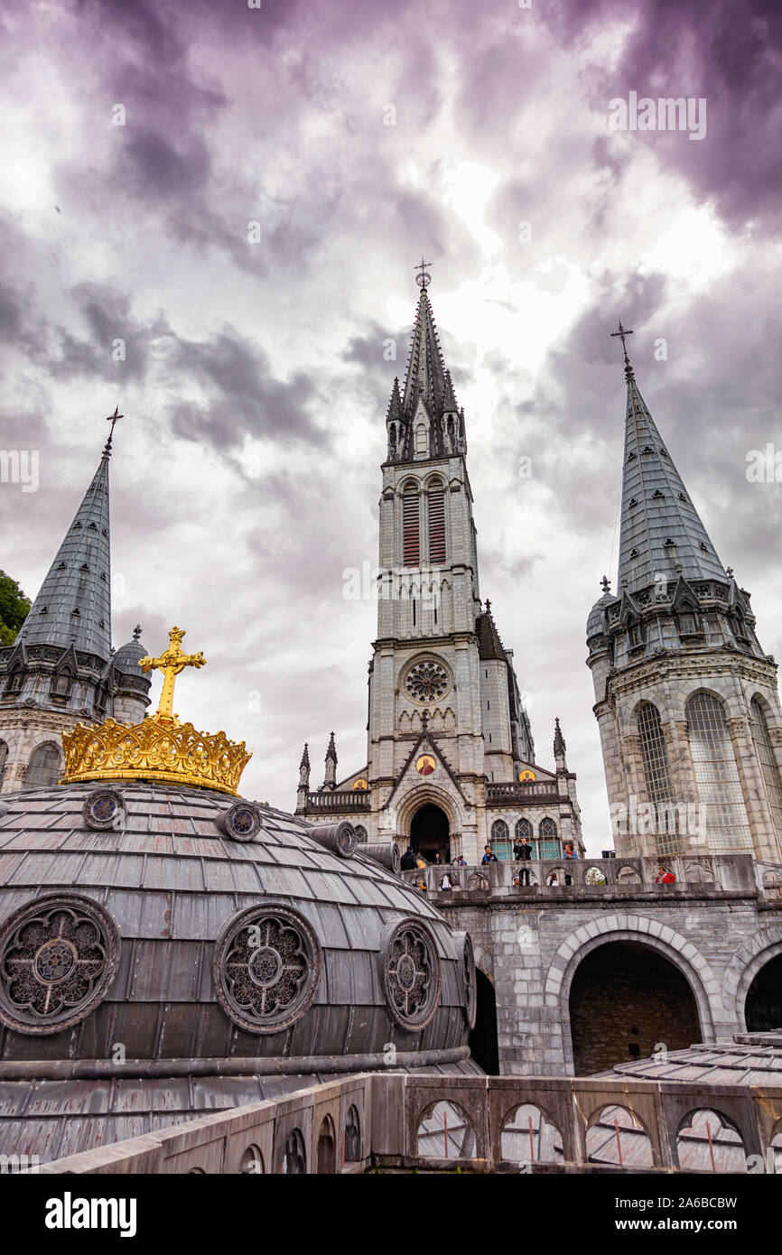 LOURDES - Giugno - 15 - 2019: una croce cristiana su uno sfondo la Basilica di Nostra Signora del Rosario a Lourdes, Francia Foto Stock