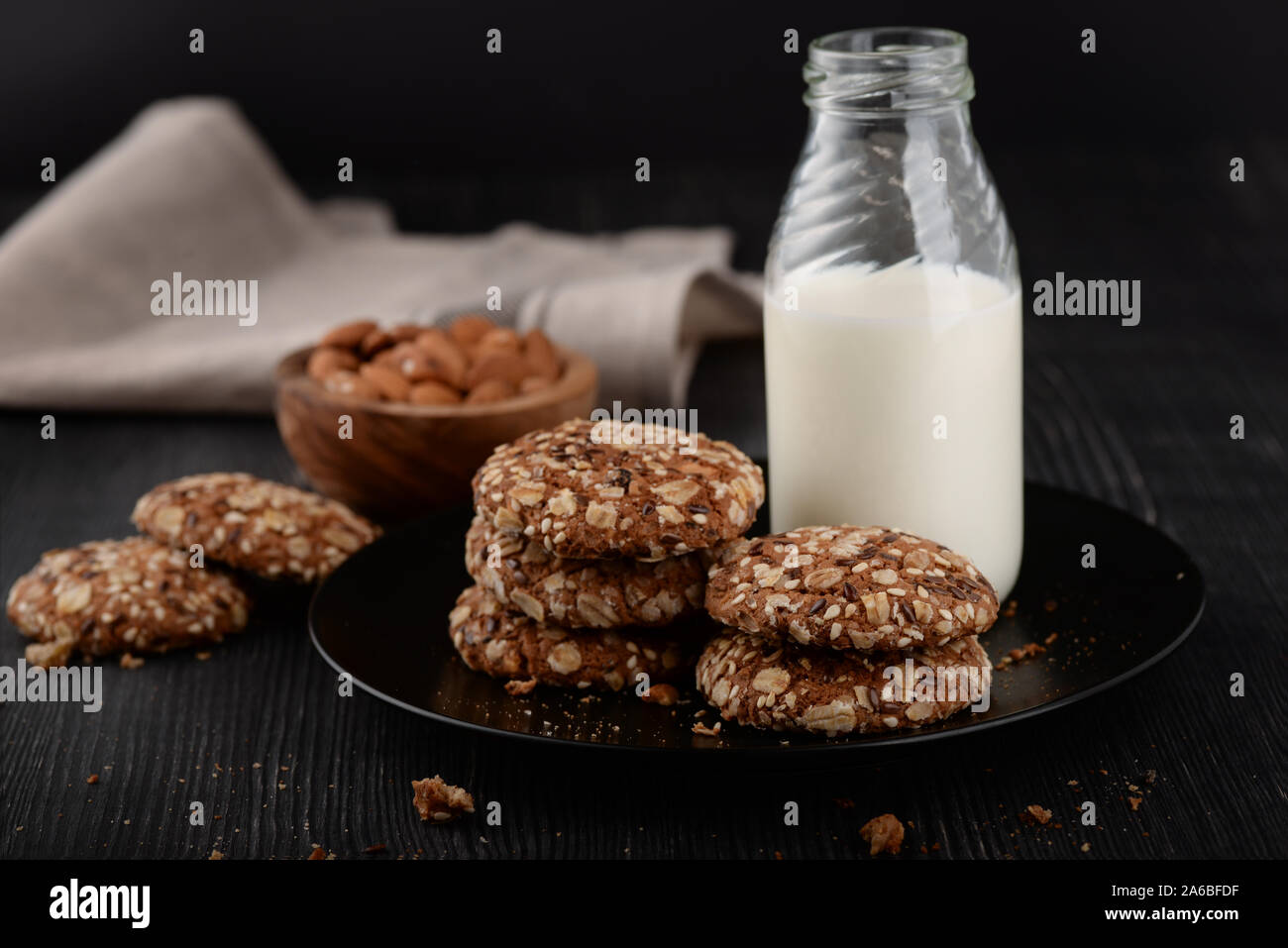 Bottiglia di latte e in casa grano intero cookie sul legno scuro dello sfondo Foto Stock
