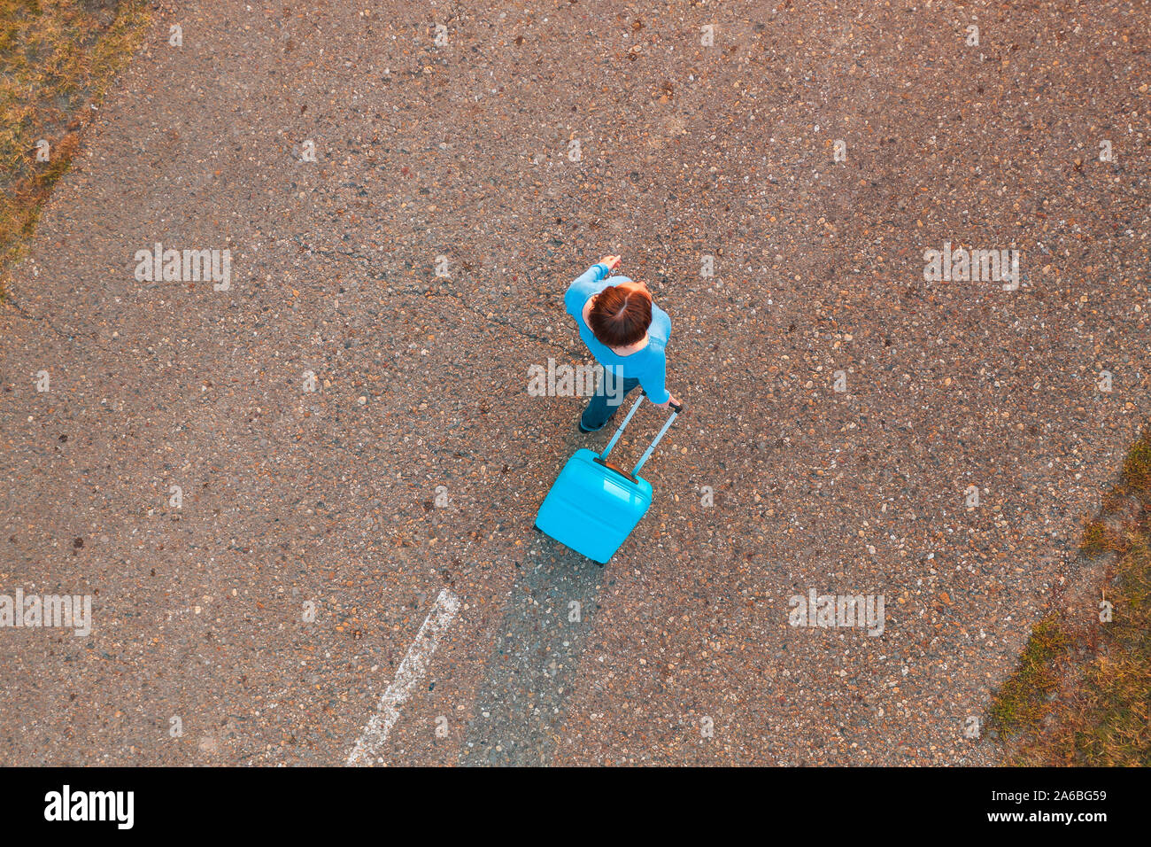 Tirando la donna valigia viaggio bagagli su strada in autunno tramonto, elevato angolo vista da fuco pov Foto Stock