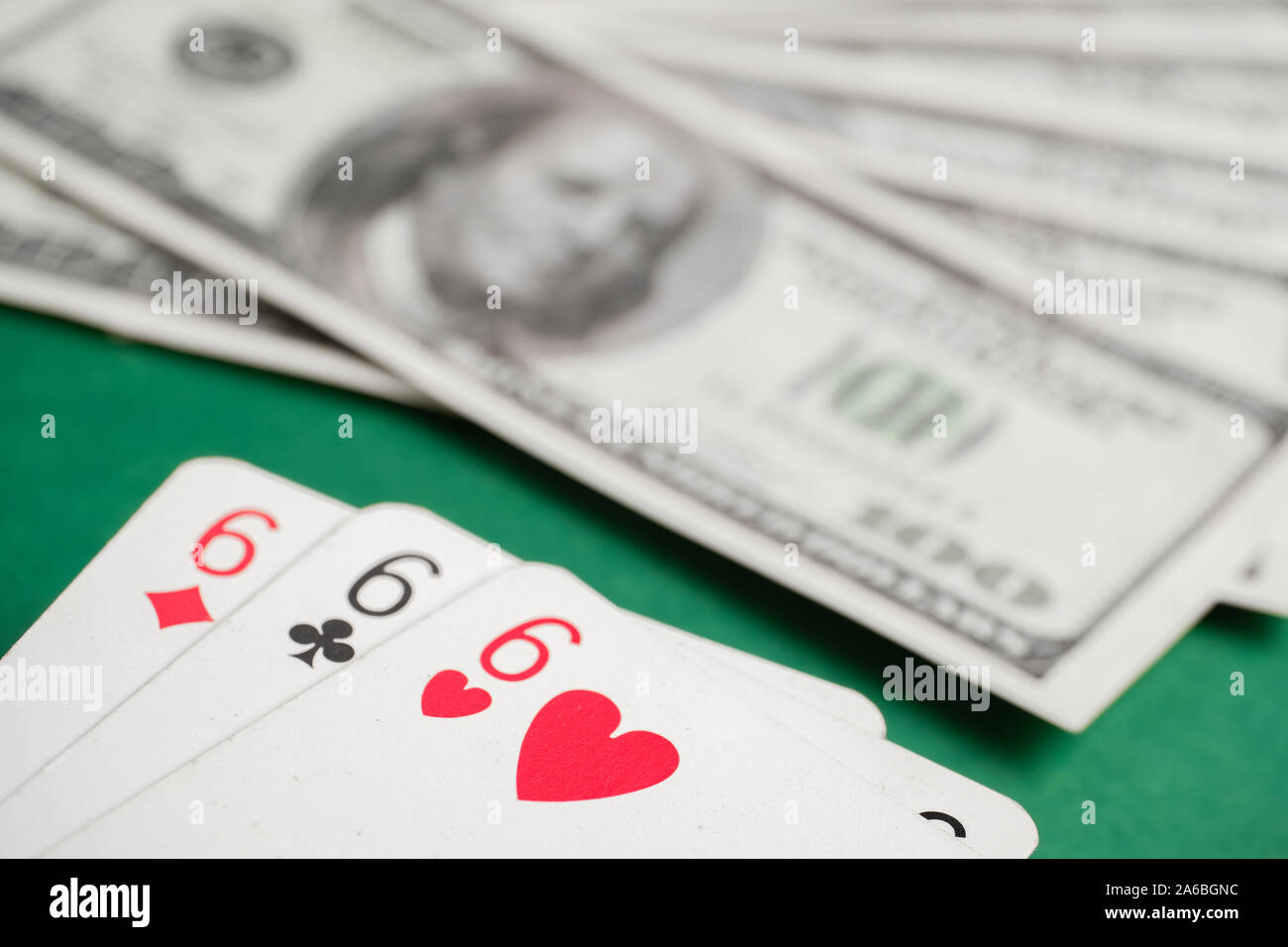Close up della combinazione di tre sixes durante il poker su sfondo di fatture del dollaro sul tavolo verde. Foto Stock