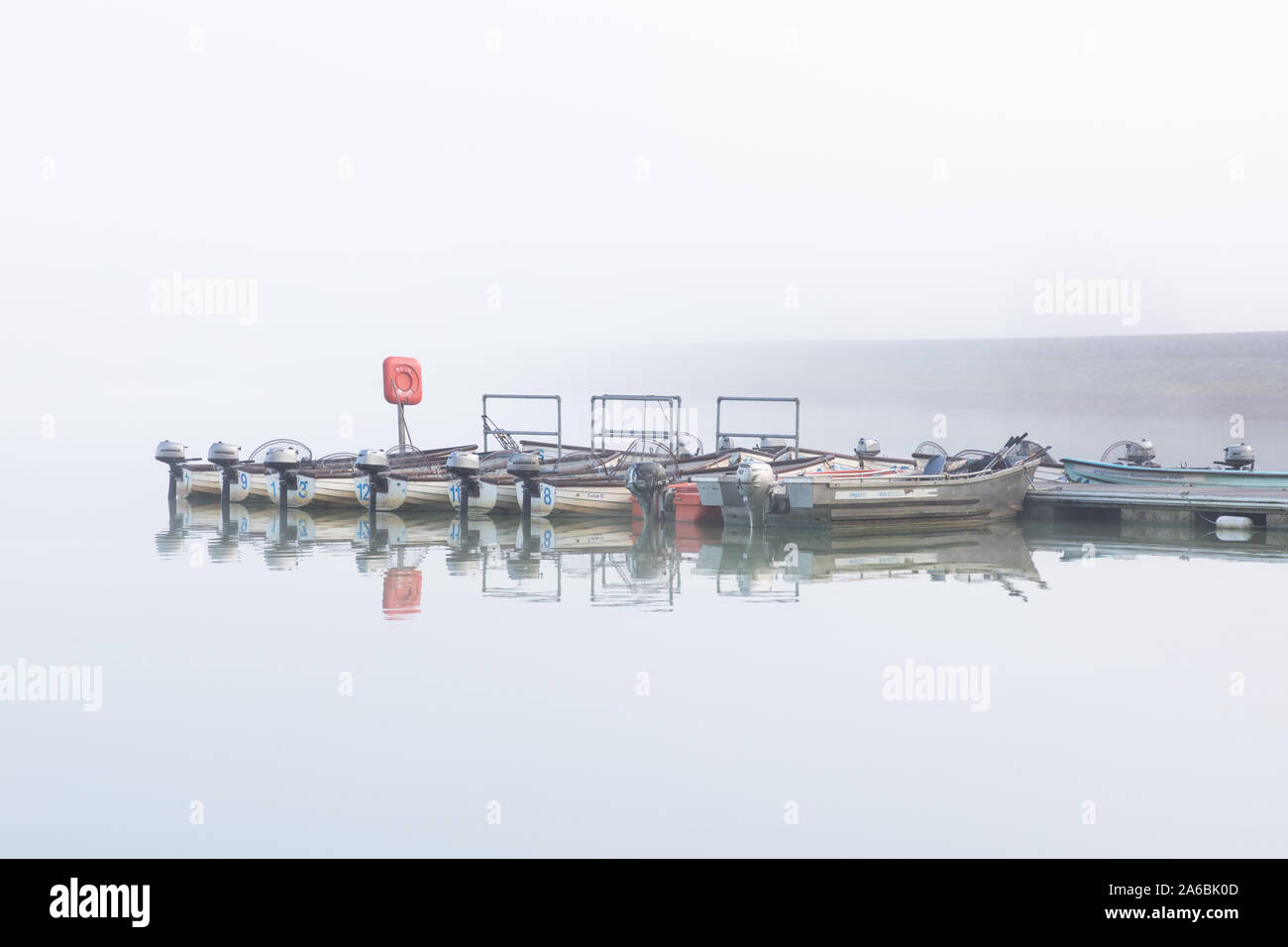 Ravensthorpe Reservoir, Northamptonshire, Regno Unito: Su una misty mattina piccole barche angling con motori fuoribordo sono ormeggiate contro un pontone. Foto Stock