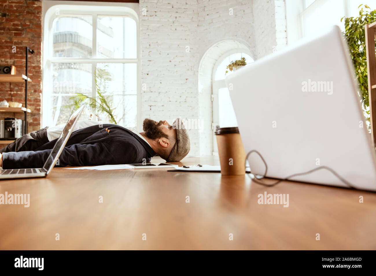 Giovane imprenditore caucasico divertirsi ballare break dance in ufficio moderno al tempo di lavoro con i gadget. Gestione, libertà, attività professionale, un modo alternativo di lavorare. Ama il suo lavoro. Foto Stock