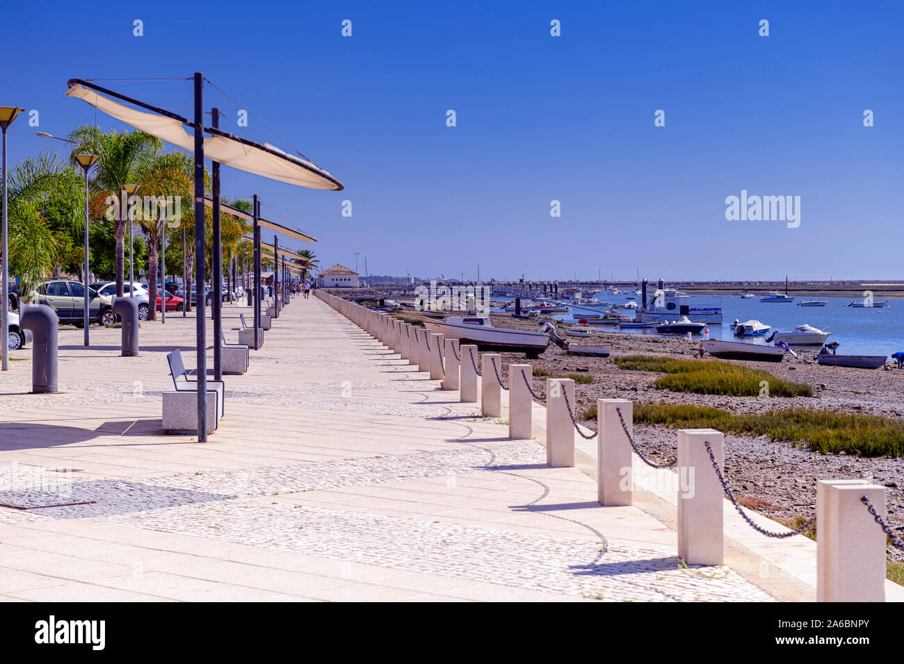 Passeggiata Santa Luzia accanto a Ria Formosa con panchine e ombrelloni. Il litorale ha la pesca e le barche da diporto Santa Luzia. Algarve, Portogallo. Foto Stock