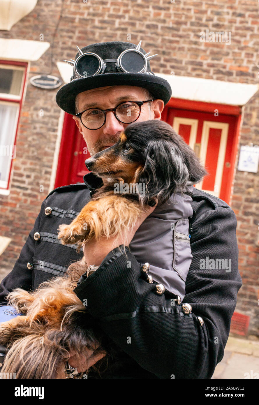 Uomo e cane in tradizionale costume di Goth, Whitby Goth Festival Weekend, Whitby, North Yorkshire, Regno Unito, 25 Ottobre 2019 Foto Stock