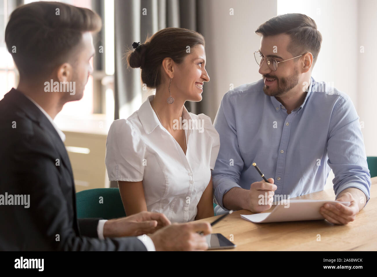 Felice giovane coppia sorridente a discutere i dettagli del contratto Foto Stock