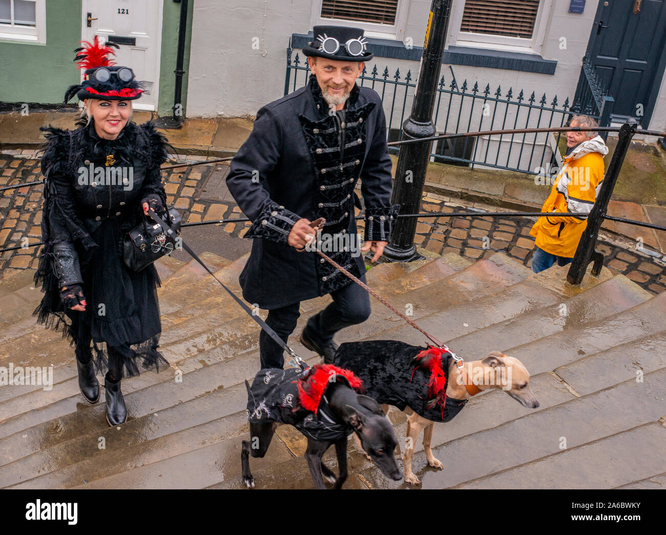 Tradizionalmente costume Goth giovane e cani salendo 199 passi a Whitby Abbey, Whitby Goth Festival Weekend, Whitby, North Yorkshire, Regno Unito, 25 Ottobre 2019 Foto Stock