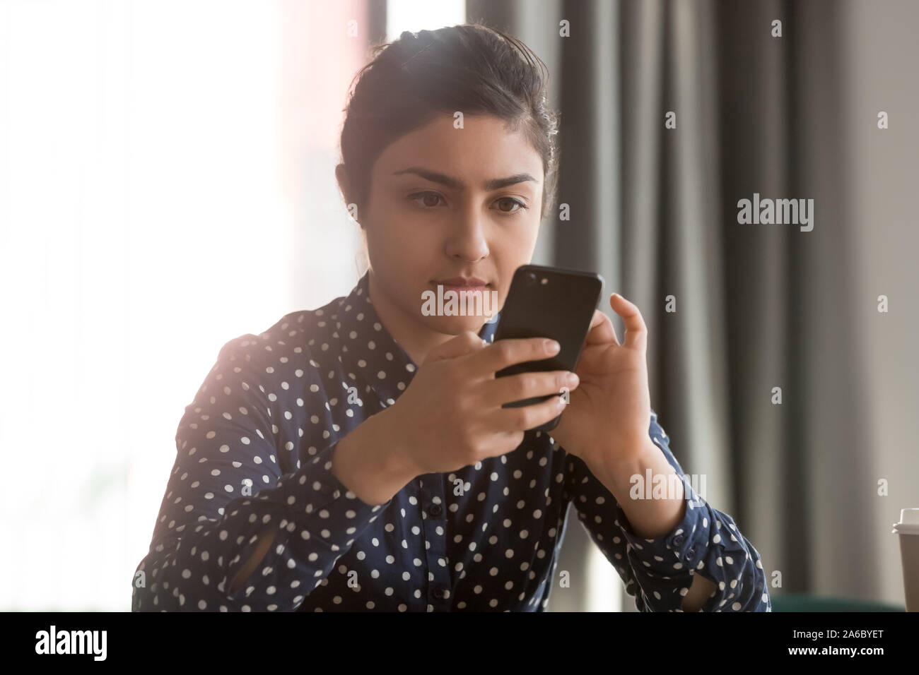 Giovane donna indiana utilizzando assistente virtuale o messaggi sms Foto Stock