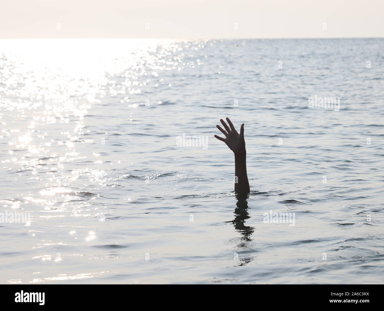 Il braccio e la mano dell'uomo sull'oceano simbolo di chiamare per ricevere assistenza Foto Stock