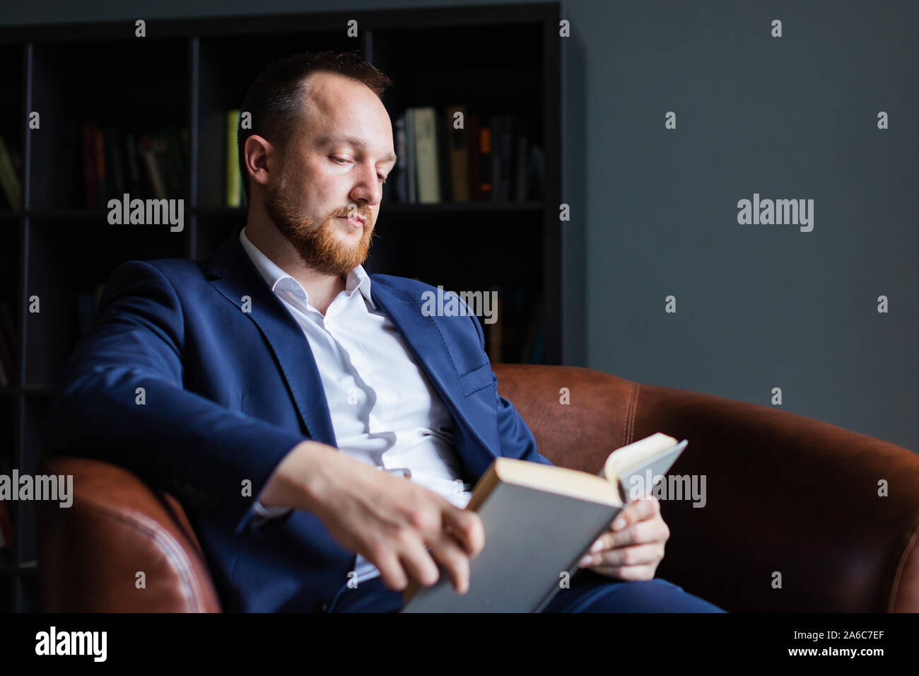 Adulto imprenditore di successo in un vestito siede la lettura di un libro. Foto Stock