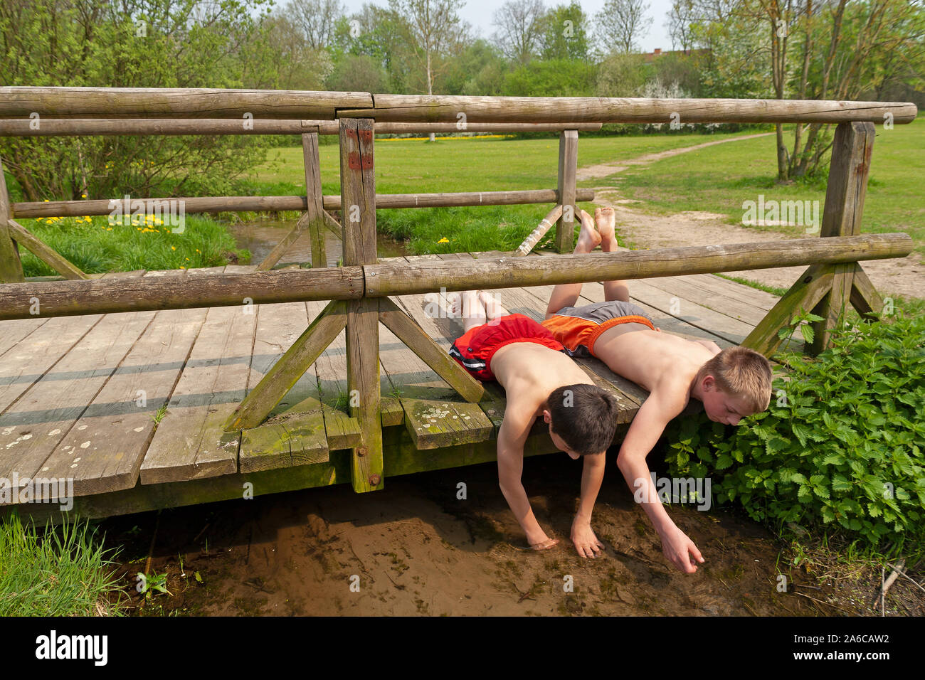 Due ragazzi sono giacenti su un ponte di legno in riproduzione in un flusso. Foto Stock