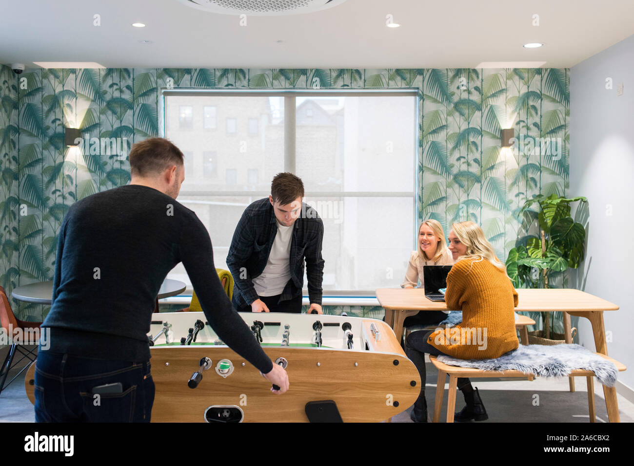 due uomini giocano a calcio balilla in una sala del personale in un ufficio creativo Foto Stock