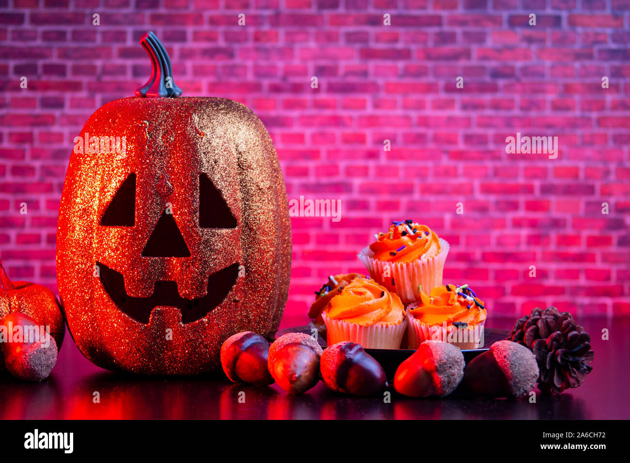 Zucca di Halloween con Halloween muffin e ornamenti con una illuminazione rossa Foto Stock