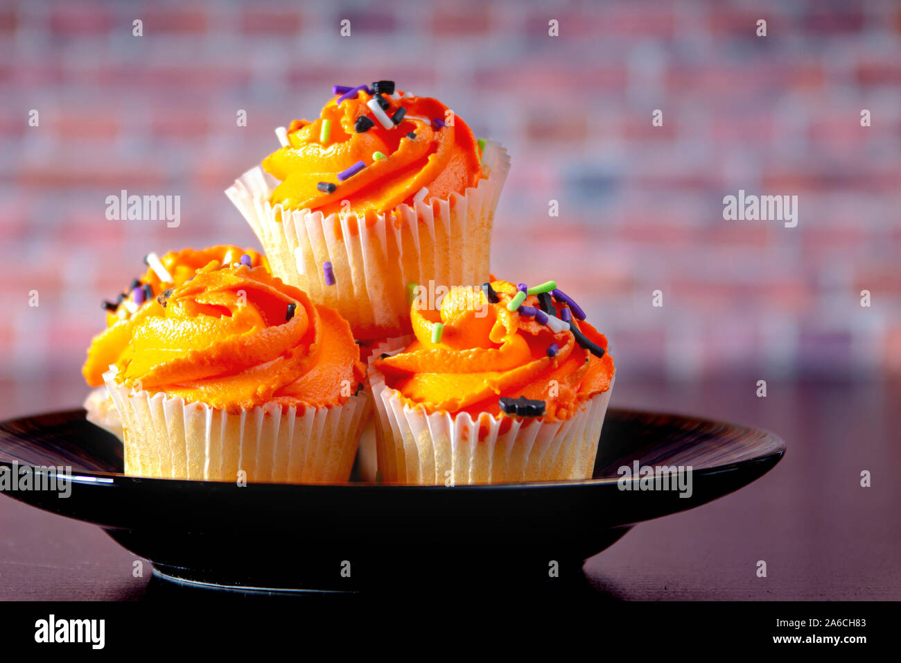 Halloween muffin su una piastra nera con un sfondo mattone Foto Stock