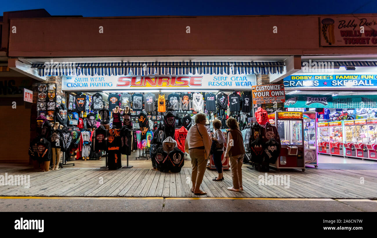 Poche persone a piedi e visitare i negozi e sale da gioco su una passerella vuota di notte quando l'estate è finita. Foto Stock