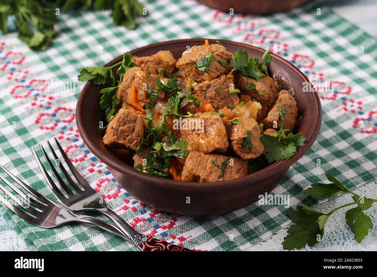 Gulasch di manzo si trova in una ciotola marrone sul tavolo Foto Stock