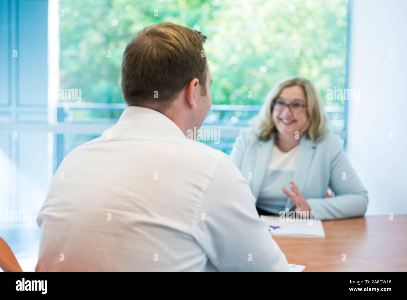 Due persone si sedette ad un tavolo avente una riunione o un colloquio di lavoro Foto Stock