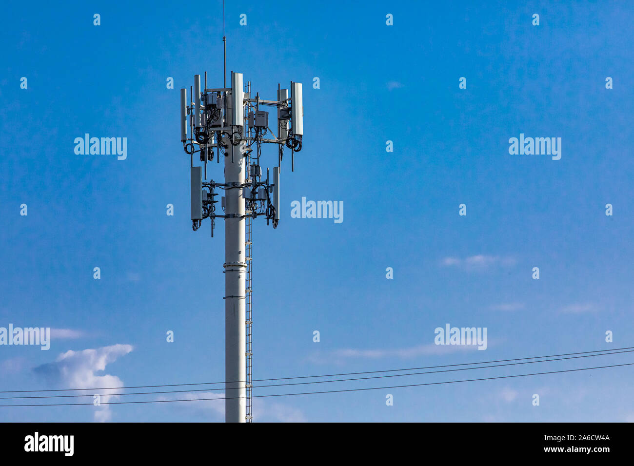 Un basso angolo di visione di un sito di cella tower per la trasmissione mobile di dati e segnali di comunicazione, comunemente associati con EMF o campo elettromagnetico inquinamento. Foto Stock