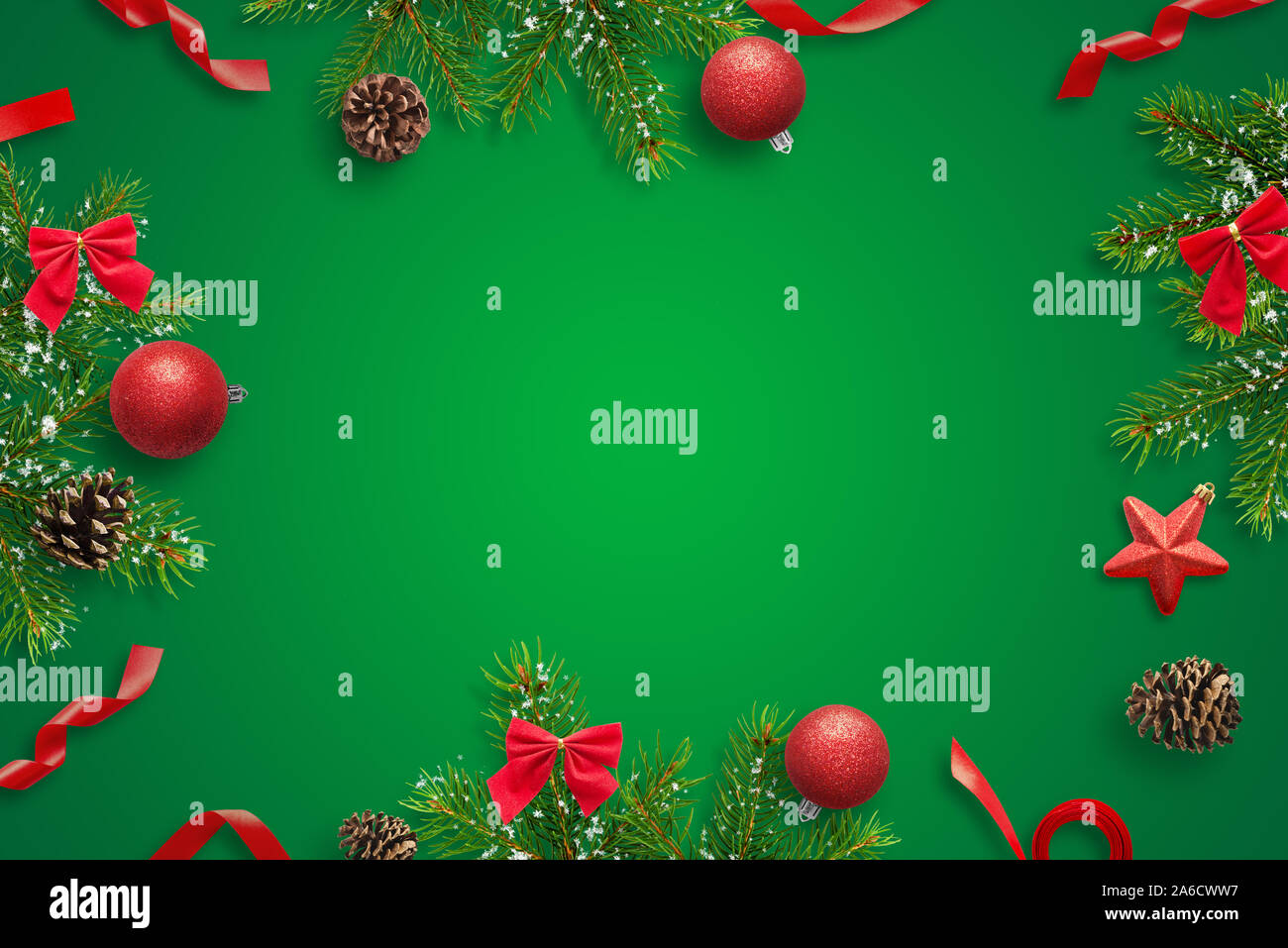 Composizione delle decorazioni di Natale sul tavolo verde con copia spazio in mezzo per il messaggio di saluto del testo. Natale biglietto di auguri. Foto Stock