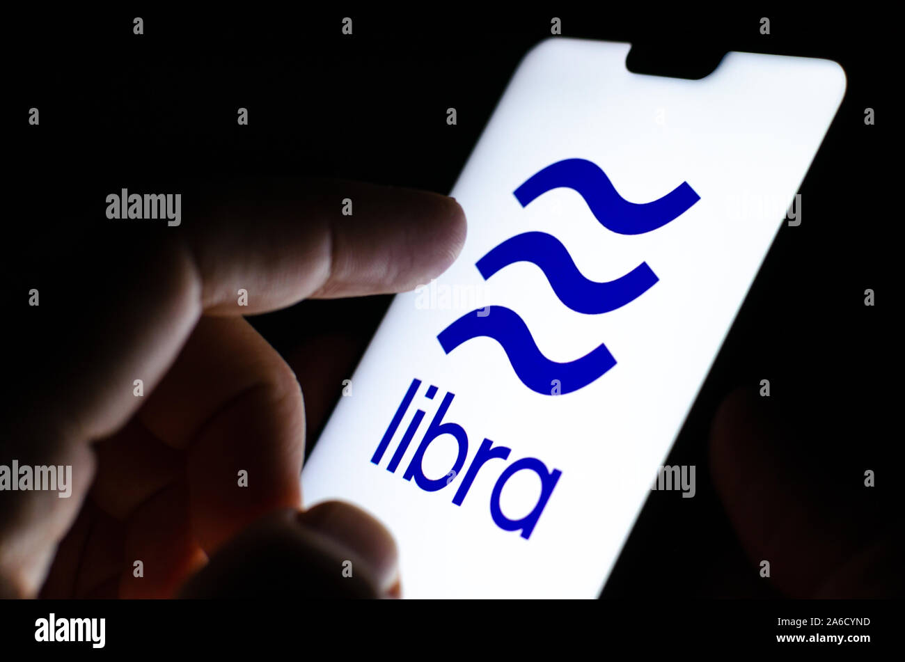 Libra valuta digitale logo su uno smartphone e dito è circa di toccarla. Messa a fuoco selettiva. Foto concettuale per Facebook Libra progetto. Foto Stock