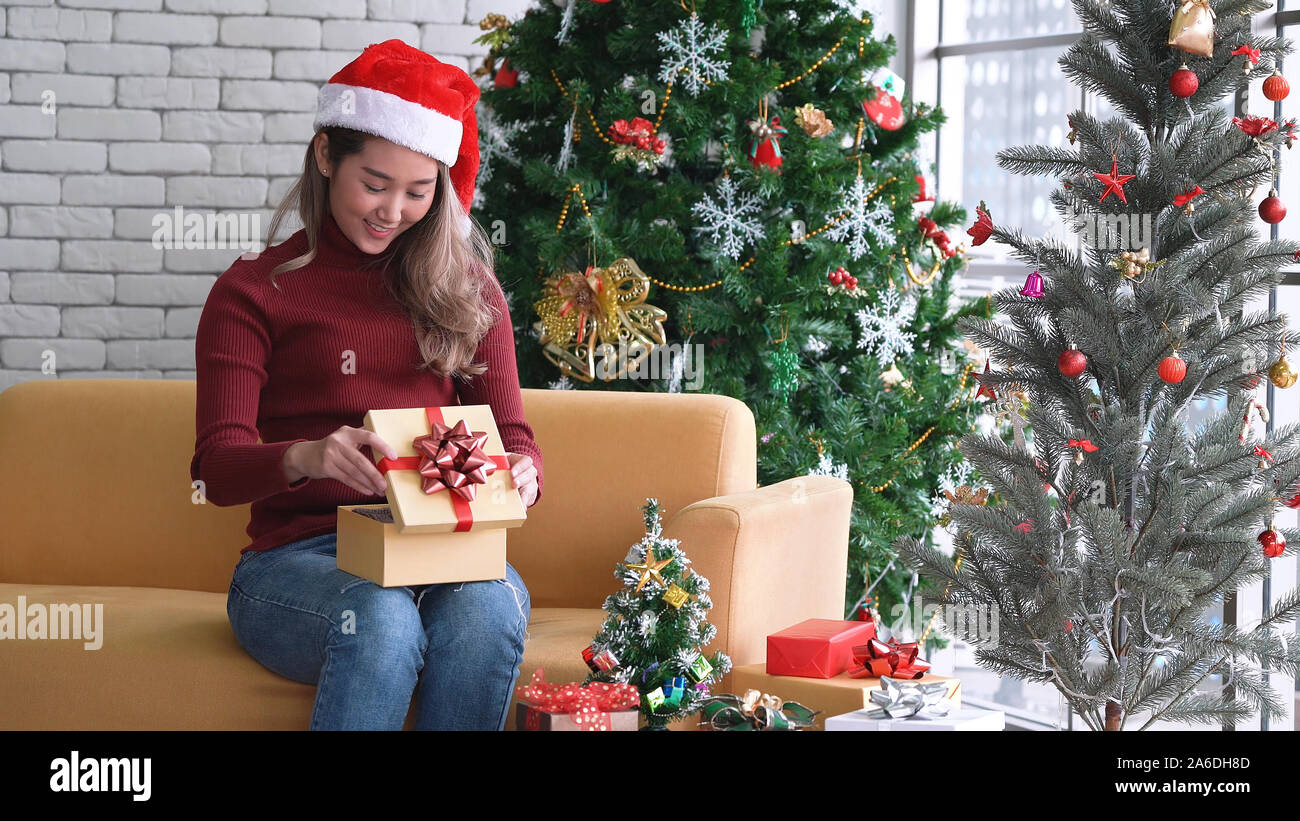 Giovane ragazza asiatica apertura confezione regalo con la faccia felice nella mattina di Natale Foto Stock