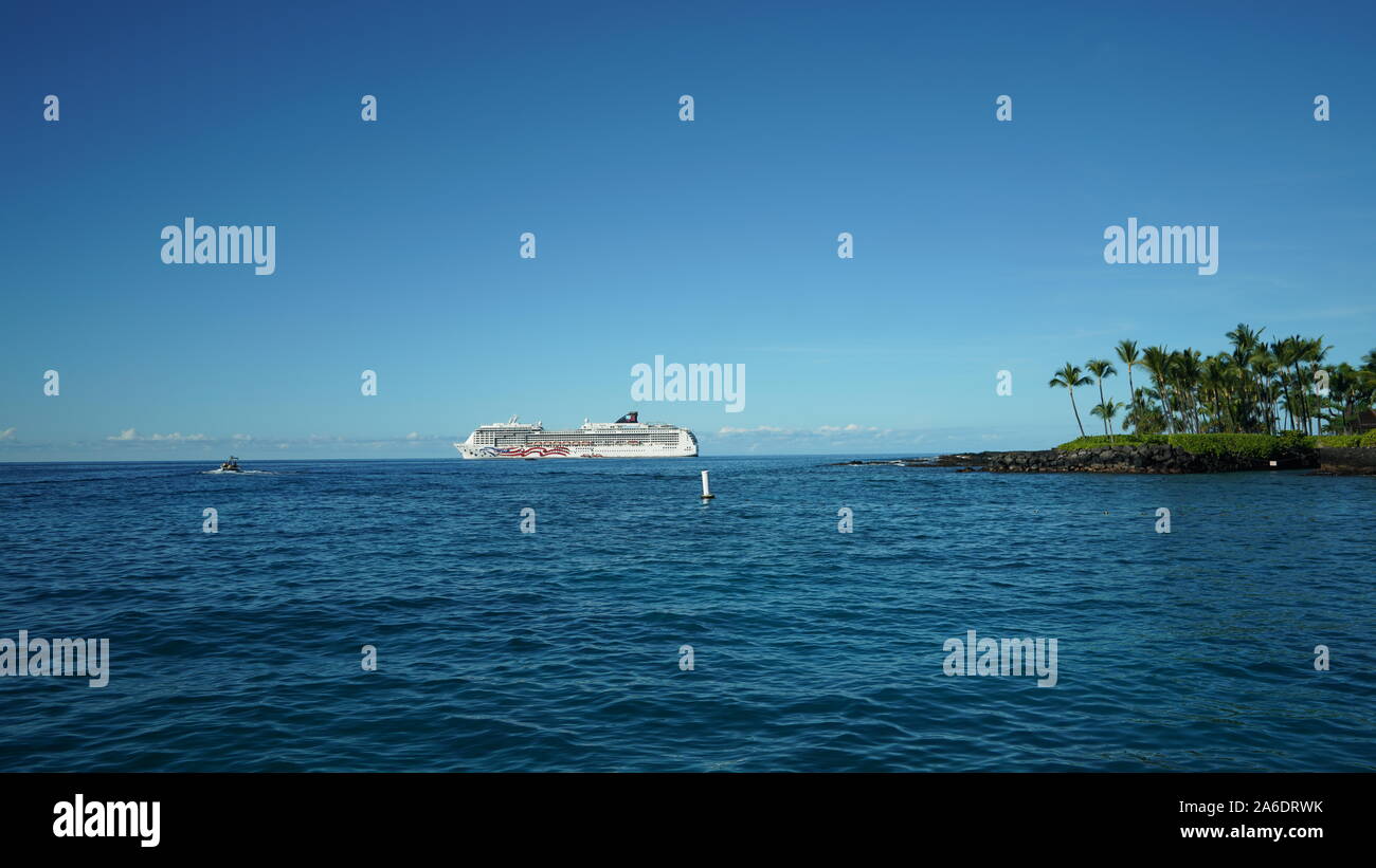 Una grande nave da crociera ancorata off Kailua Kona Bay nelle Hawaii Big Island, palme sulla terra, Oceano Pacifico incontra il cielo blu in corrispondenza della linea di orizzonte Foto Stock