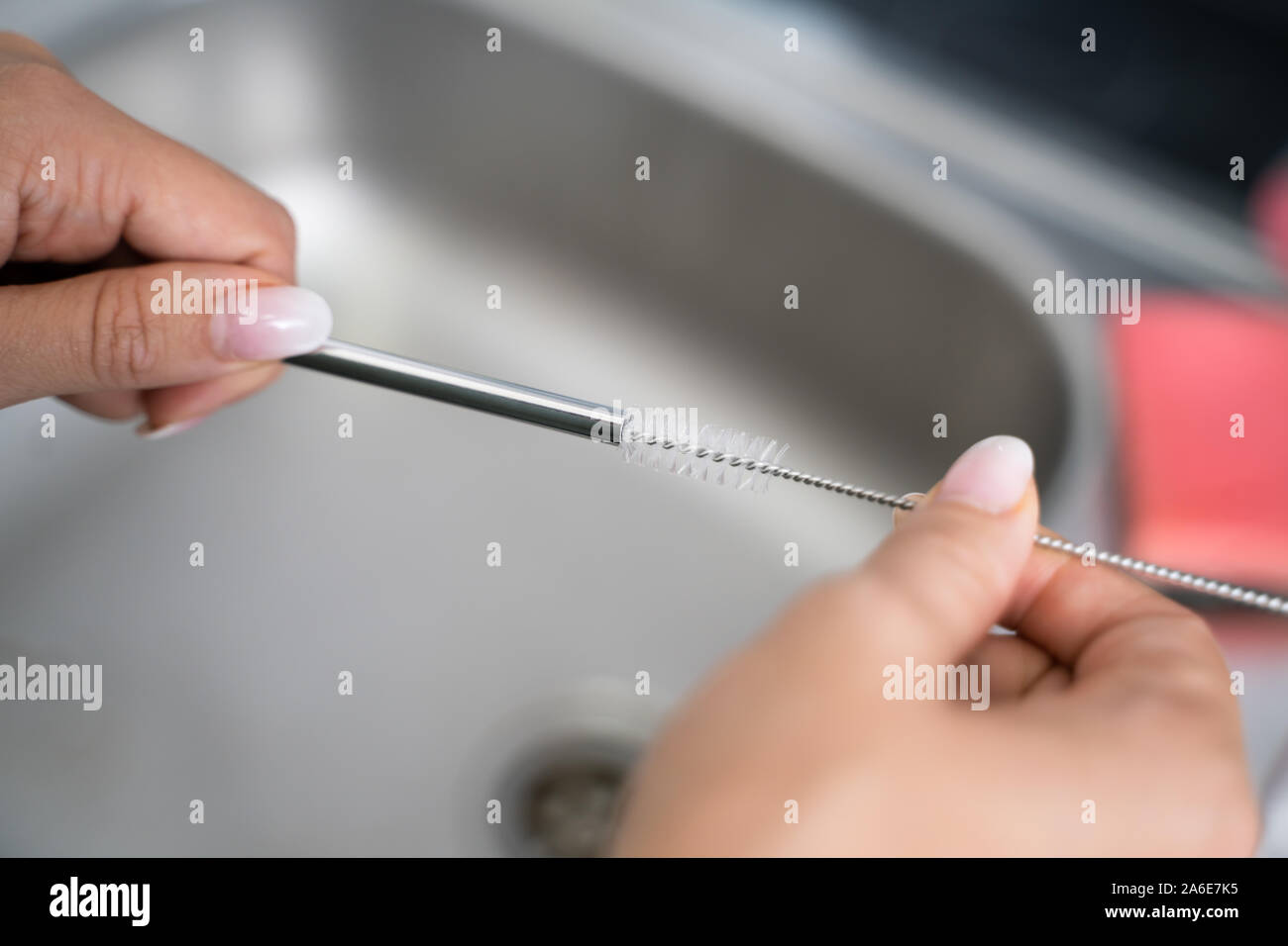 Donna di pulizia metallo riutilizzabili paglia in cucina Foto Stock