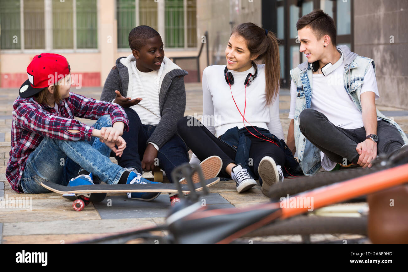 Sorridente ragazza spagnola e tre ragazzi appendere fuori all'aperto e discutere di un argomento Foto Stock