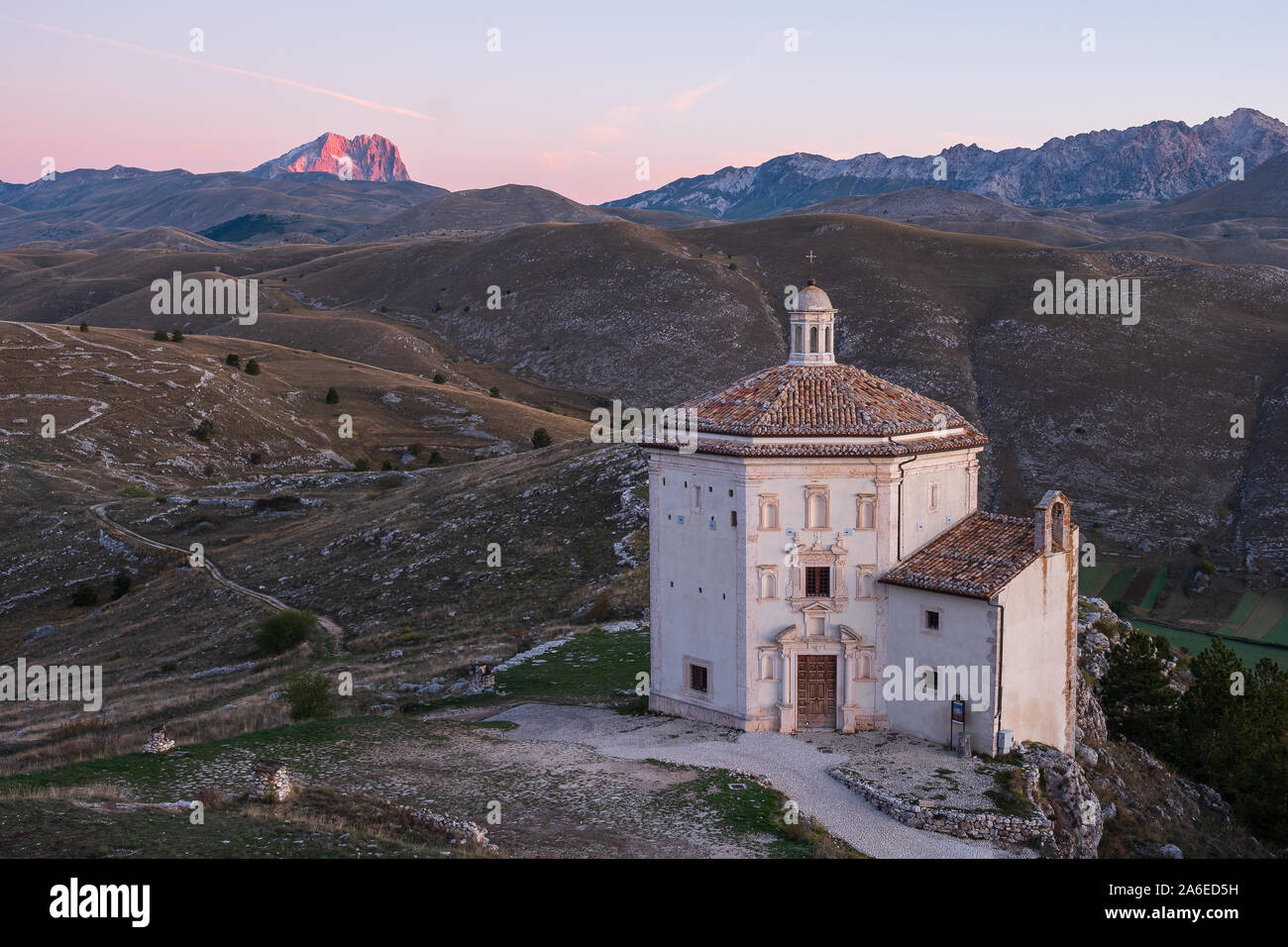 Cappella bella Chiesa di Santa Maria della Pietà a sunrise con paesaggio arido e alpino incandescente montagna di Corno Grande in background, Rocca C Foto Stock