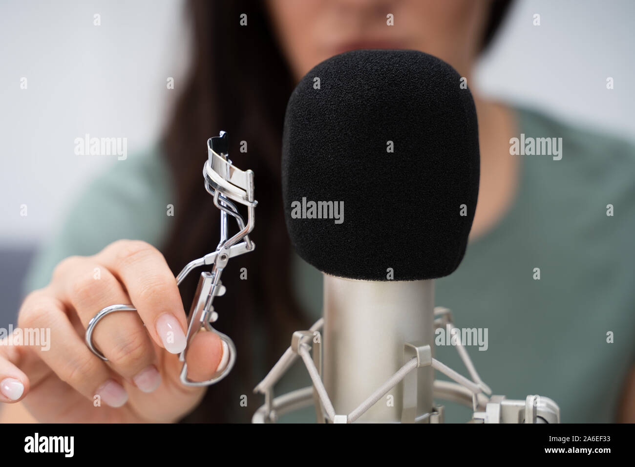 Donna che utilizza il ciglio Bigodino sul microfono per rendere i suoni ASMR Foto Stock