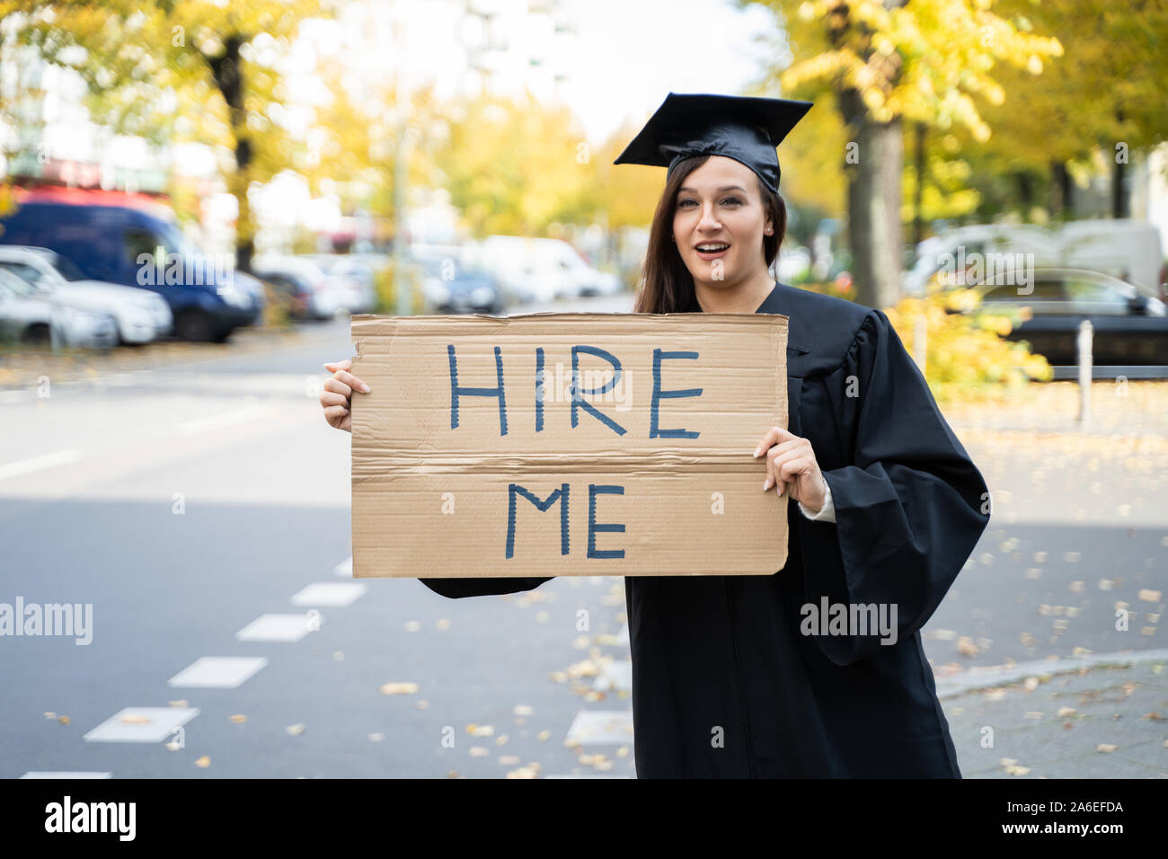 Studente laureato in piedi con noleggio di Me sulla targhetta Street Foto Stock