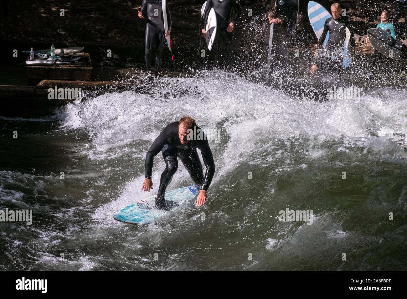 Un surfista Cavalca le onde artificiali a Eisbachwelle, Monaco di Baviera, Germania. Parte di un uomo fatto river, lo spot è utilizzato per una navigazione annuale concorso. Foto Stock