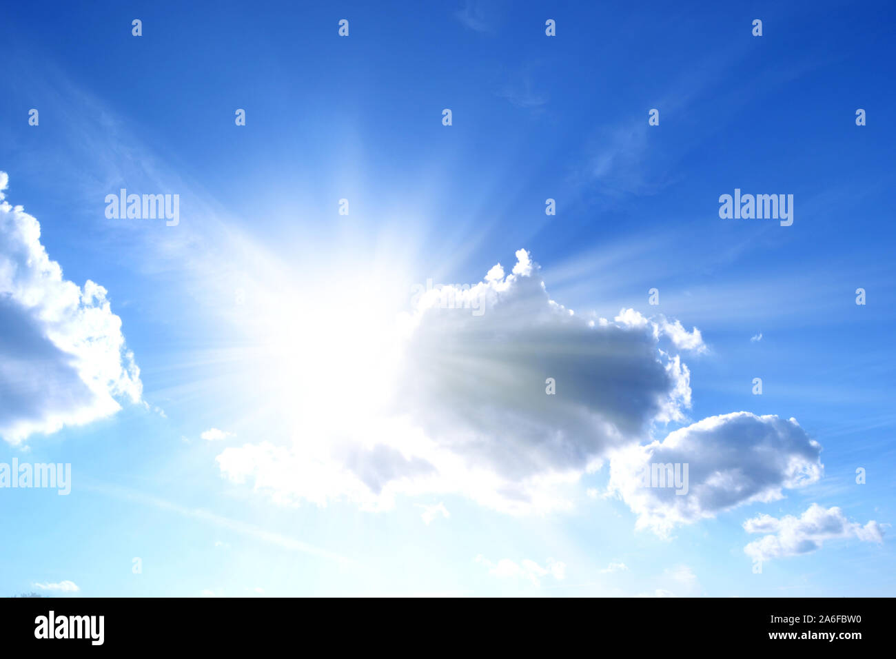 La luce del sole dietro le nuvole nel cielo blu Foto Stock