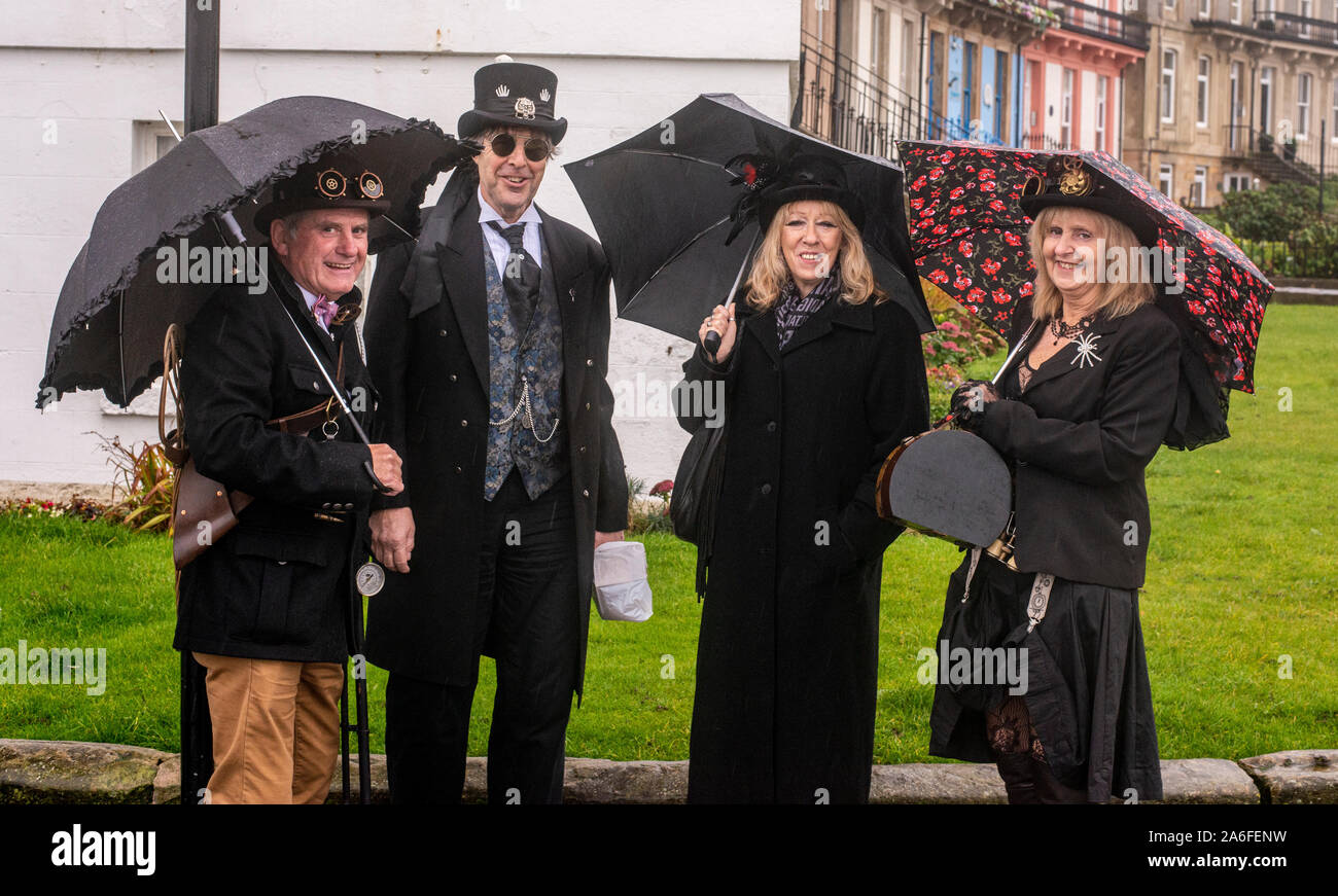Gruppo di persone jolly nei tradizionali costumi di Goth in piedi nella pioggia, Whitby Goth Festival Weekend, Whitby, North Yorkshire, Regno Unito, 26 Ottobre 2019 Foto Stock